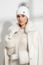Įkelti nuotrauką į galerijos peržiūros programą, A woman wearing a white knit beanie with a gray faux-fur pom-pom, white gloves, a cream knit sweater, and a white coat with fluffy fur trim, posed against a clean white studio background.
