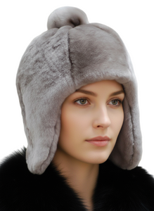 Woman wearing a gray fur hat with ear flaps against a blurred background