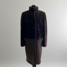 Įkelti nuotrauką į galerijos peržiūros programą, A dark brown fur jacket with a high collar displayed on a mannequin, paired with a dark brown leather skirt, against a neutral gray background.
