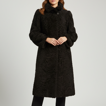 Įkelti nuotrauką į galerijos peržiūros programą, A woman modeling a long black textured faux-fur coat with a high collar, paired with black pants and black ankle boots, against a light gray studio background.
