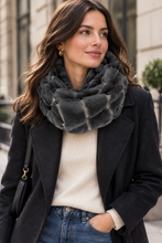 Įkelti nuotrauką į galerijos peržiūros programą, A woman wearing a chunky, textured dark gray faux fur scarf, styled with a black coat, cream ribbed sweater, and blue jeans in an outdoor urban setting.
