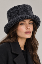 Įkelti nuotrauką į galerijos peržiūros programą, A close-up of a woman wearing a dark charcoal gray chunky knit bucket hat and a black coat against a light gray background.
