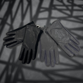 Pair of black gloves on a textured surface with shadow patterns