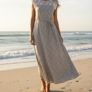 Woman in a dress standing on a beach with ocean waves in the background