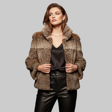 Įkelti nuotrauką į galerijos peržiūros programą, A woman modeling a cropped, textured faux fur jacket in mixed brown and beige tones, paired with a black satin top and black faux leather pants, against a solid gray background.
