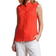 A woman modeling a sleeveless bright orange-red button-front top with a stand collar and white pants, photographed against a plain white studio background.