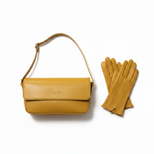 Įkelti nuotrauką į galerijos peržiūros programą, A mustard yellow leather shoulder bag with a flap closure and a matching pair of leather gloves, displayed on a clean white background.
