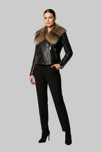Įkelti nuotrauką į galerijos peržiūros programą, A model wearing a black leather moto jacket with a large brown fur collar, paired with black trousers and black high-heeled boots, set against a solid gray background.
