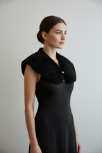 Įkelti nuotrauką į galerijos peržiūros programą, A woman in a black sleeveless dress wearing a wide black textured knit collar or shrug, posed against a plain light gray studio background.
