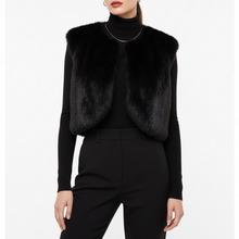 Įkelti nuotrauką į galerijos peržiūros programą, A model wearing a black faux fur vest over a black long-sleeve turtleneck and black trousers, shown from the lips down against a plain white background.
