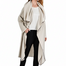 Įkelti nuotrauką į galerijos peržiūros programą, A woman modeling a long, draped beige wrap coat over a white top, black cropped pants, and black platform sneakers against a plain white background.
