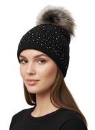 Woman wearing a black beanie with a fur pom-pom on a light gray background