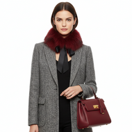 Woman wearing a gray coat with a red fur collar and holding a matching red handbag on a white background