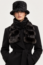Load image into Gallery viewer, A model wearing a black textured knit bucket hat, a matching black knit scarf with faux fur trim, and a black belted coat against a light gray studio background.
