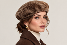 Įkelti nuotrauką į galerijos peržiūros programą, A woman wearing a brown faux fur beret and a brown coat over a cream turtleneck, with gold earrings, photographed against a light gray studio background.

