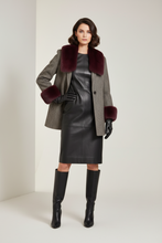 Įkelti nuotrauką į galerijos peržiūros programą, A model stands in a studio wearing a gray herringbone coat with deep burgundy fur trim at the collar and cuffs, a black faux-leather dress, black gloves, and black knee-high boots.
