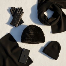 Įkelti nuotrauką į galerijos peržiūros programą, Collection of black winter accessories including gloves, hats, and a phone on a light background
