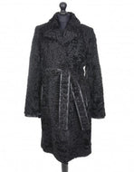 Black astrakhan knee-length coat with a tie, featuring a regular collar, pockets at the front, and fur hooks fastening. The coat is lined and has deep vents at the back.