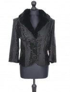 A black astrakhan fur lined jacket with a mandarin collar, button fastening, and small front pockets, displayed on a mannequin.