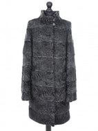 Dark grey astrakhan knee-length coat with decorative textile inserts, stand collar, front pockets, and fur hooks fastening. It is displayed on a mannequin with a visible label.