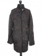 A dark brown astrakhan short coat with decorative textile inserts, featuring front pockets and fur hooks fastening, displayed on a mannequin.