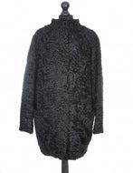 Black astrakhan cacoon type coat with pockets at the front and fur hooks fastening, displayed on a mannequin.