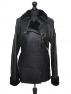 A black, long Nappa merino sheepskin fur jacket with buttons, a collar, and front pockets, displayed on a mannequin.
