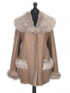 A brown sheepskin coat with a fur collar and cuffs, featuring a loose silhouette and button fastening. The coat is displayed on a mannequin.