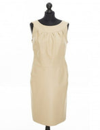 Beige color, sleeveless, fitted midi length dress with a round neckline and an invisible zipper in the back, displayed on a mannequin.