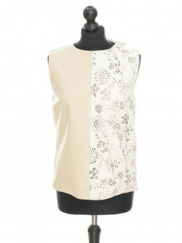 Beige and white sleeveless leather blouse with round neckline and laser perforated leather in front, lining, displayed on a mannequin.