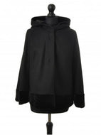 Black hooded wool cloak with velour trimming, displayed on a mannequin, with press-studs fastening.