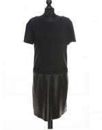 A black color knitted fabric midi length dress with perforated leather detail and pocket imitation in front, short sleeves, and an invisible zipper at the back.