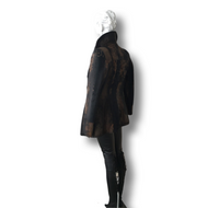 A black short goat fur jacket on a mannequin, featuring a straight silhouette with notched lapels, buttons, and a lining. The mannequin is dressed in a similar style with leather.