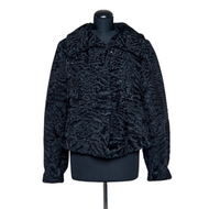 Black astrakhan fur short jacket displayed on a mannequin with fur hooks fastening and a slightly fitted silhouette.