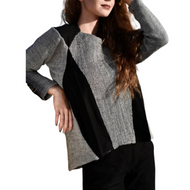 A woman wearing a color-blocked linen cardigan in gray and black, paired with black pants.