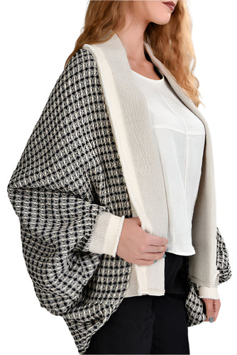 A woman wearing a linen loos mid length cardigan with a geometric pattern in black and white, with long sleeves.